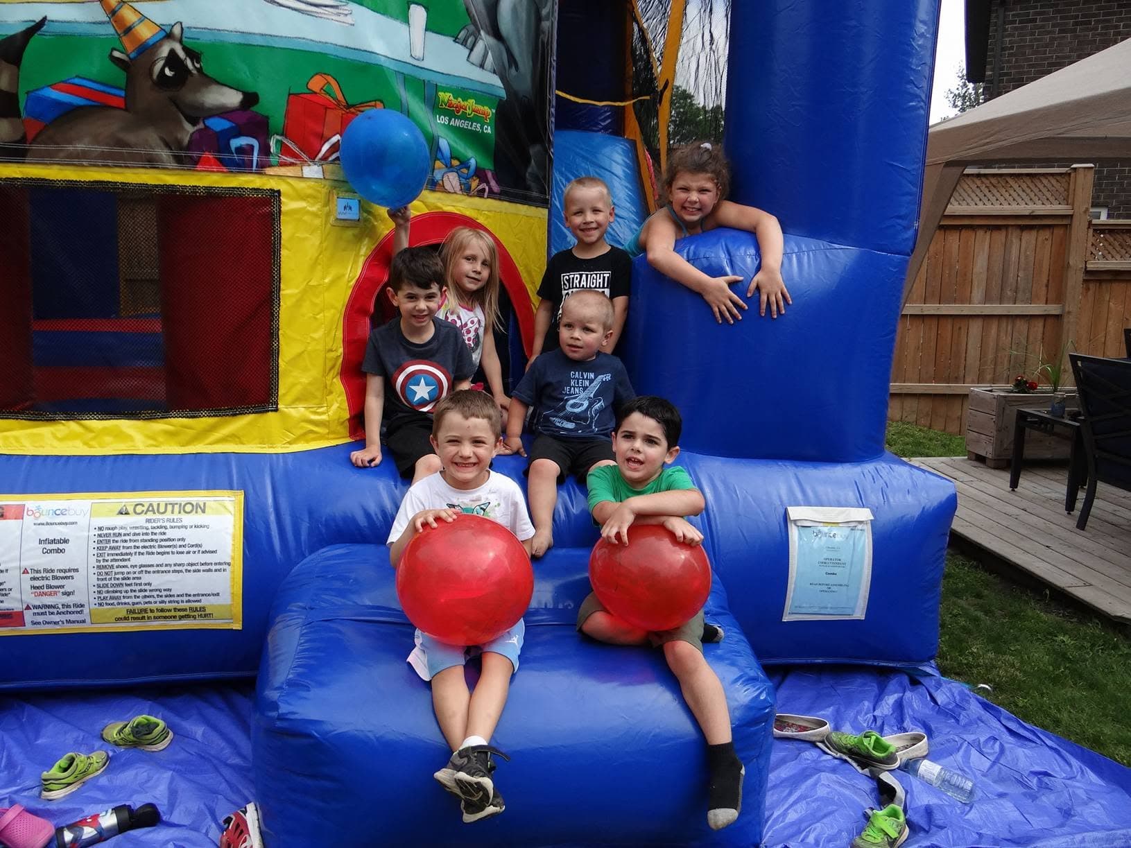 A group of happy kids sitting on a bouncy castle at a backyard party