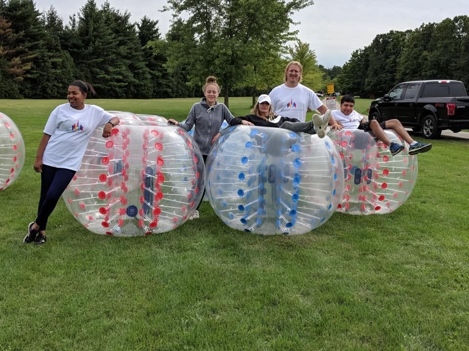 A group ready to play bubble soccer with bumper balls on the grass